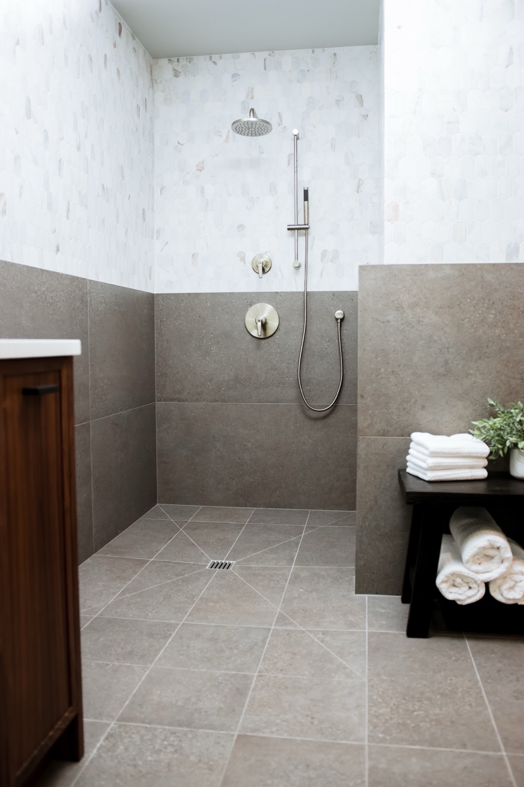 Light bathroom shower with geometric tile and a bench