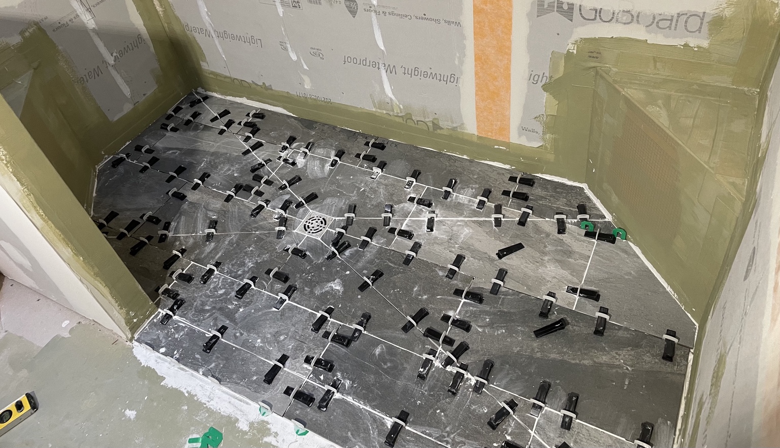 Shower floor tile being installed with leveling clips