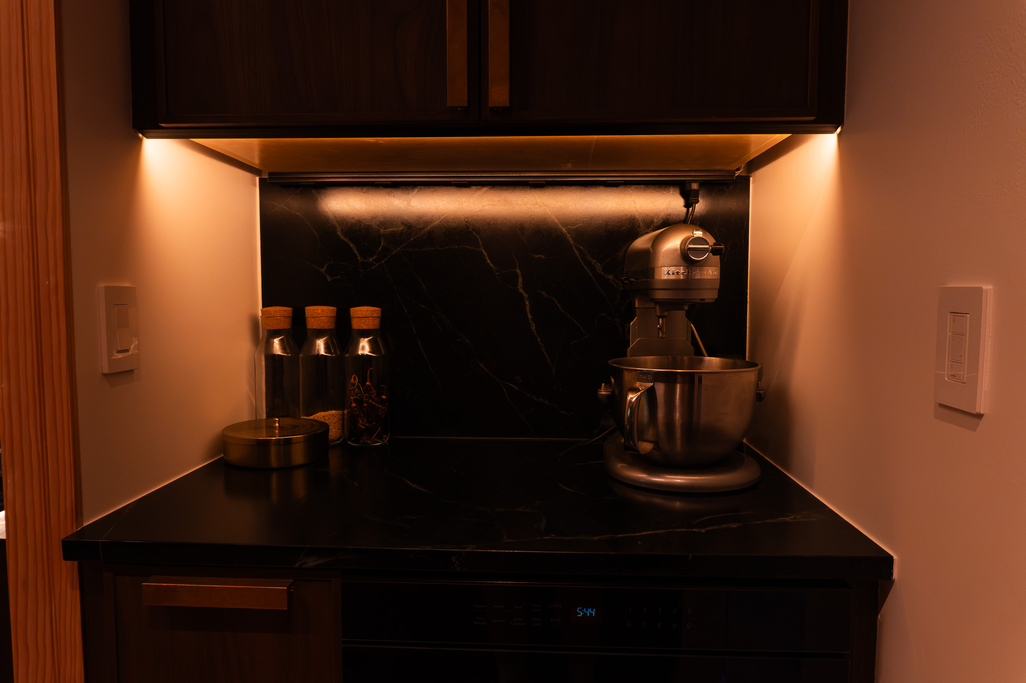 Kitchen alcove with a mixer and dark wood cabinetry